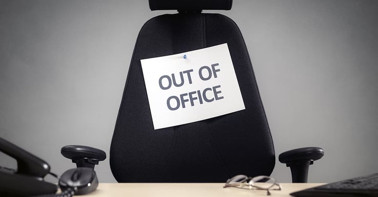 Out of office sign pinned to a black office chair-min